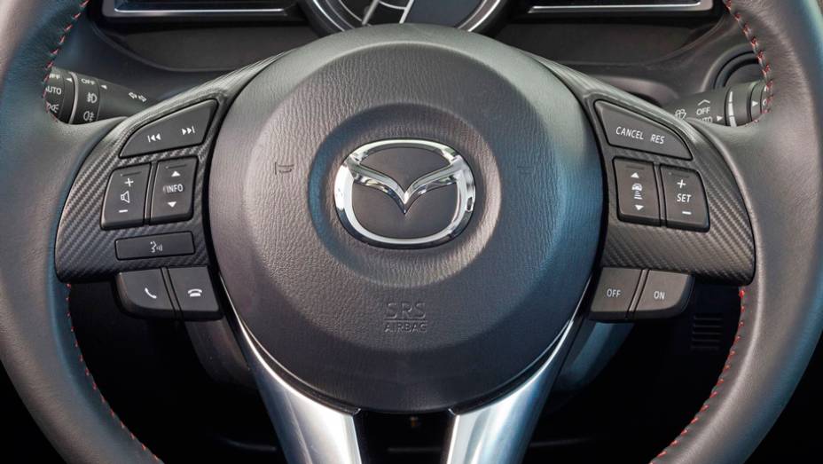 Detalhe do volante do novo Mazda3 Sedan | <a href="https://preprod.quatrorodas.abril.com.br/noticias/fabricantes/primeiras-fotos-oficiais-mazda3-sedan-2014-sao-reveladas-745927.shtml" rel="migration">Leia mais</a>