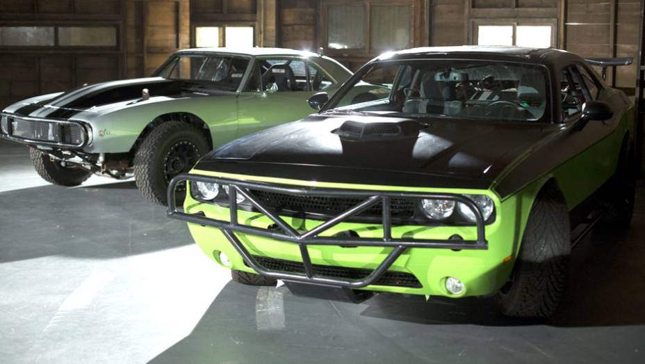 Além do Cuda, Letty também pilota um Dodge Challenger verde bastante modificado; ao fundo, o Chevrolet Camaro de Roman Pearce (Tyrese Gibson) | <a href="https://preprod.quatrorodas.abril.com.br/galerias/especiais/gatas-velozes-furiosos-852096.shtml" target="_blank" rel="migration">7</a>