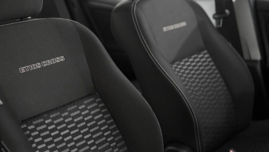 O revestimento Sport Comfort nos bancos ganhou costura branca e apresenta o nome do veículo gravado em alto relevo no encosto dos assentos dianteiros | <a href="https://preprod.quatrorodas.abril.com.br/carros/lancamentos/toyota-etios-cross-759424.shtml" rel="migration"></a>