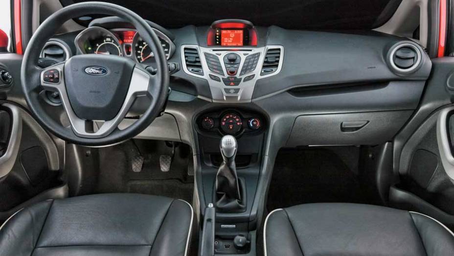 Formato dos botões centrais não favorece a ergonomia | <a href="https://preprod.quatrorodas.abril.com.br/carros/comparativos/ford-new-fiesta-x-chevrolet-sonic-699387.shtml" rel="migration">Leia mais</a>