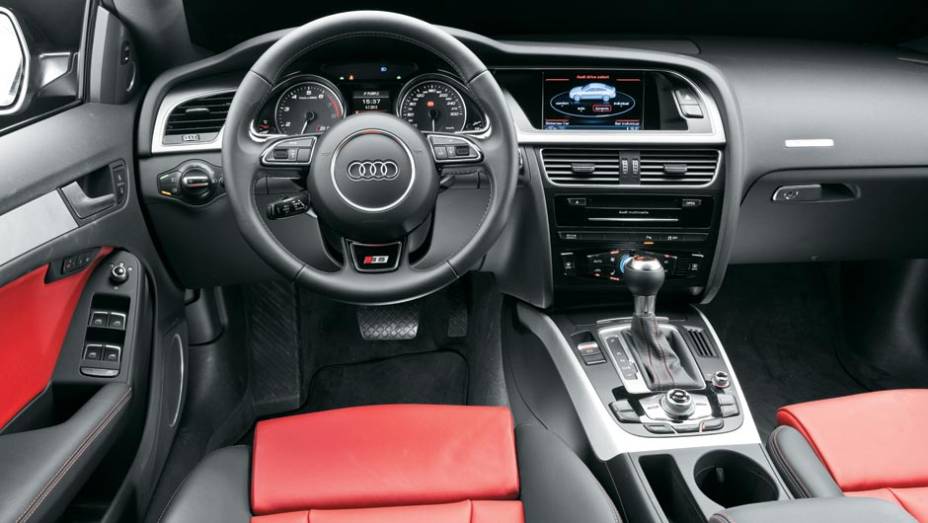 Console central, voltado para o piloto e alto entre os bancos, facilita a ergonomia. O S5 vem completo de série | <a href="https://preprod.quatrorodas.abril.com.br/carros/testes/audi-s5-700509.shtml" rel="migration">Leia mais</a>