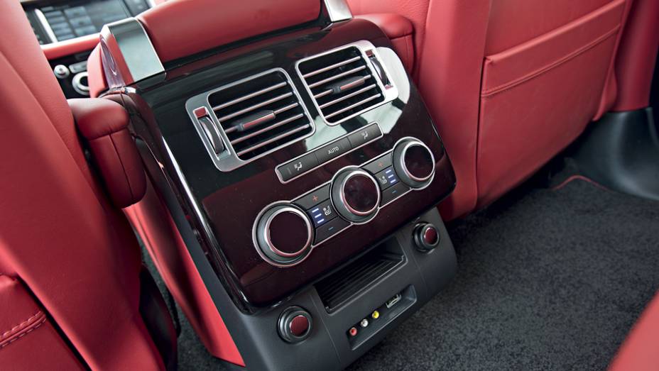 Atrás, um console abriga controles de ventilação e entrada auxiliar | <a href="https://preprod.quatrorodas.abril.com.br/carros/testes/land-rover-range-rover-vogue-738240.shtml" rel="migration">Leia mais</a>