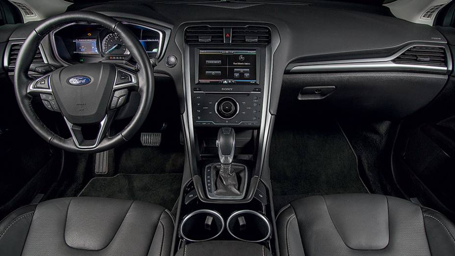 O volante &eacute; multifuncional | <a href="https://preprod.quatrorodas.abril.com.br/carros/testes/ford-fusion-hybrid-757087.shtml" rel="migration">Leia mais</a>