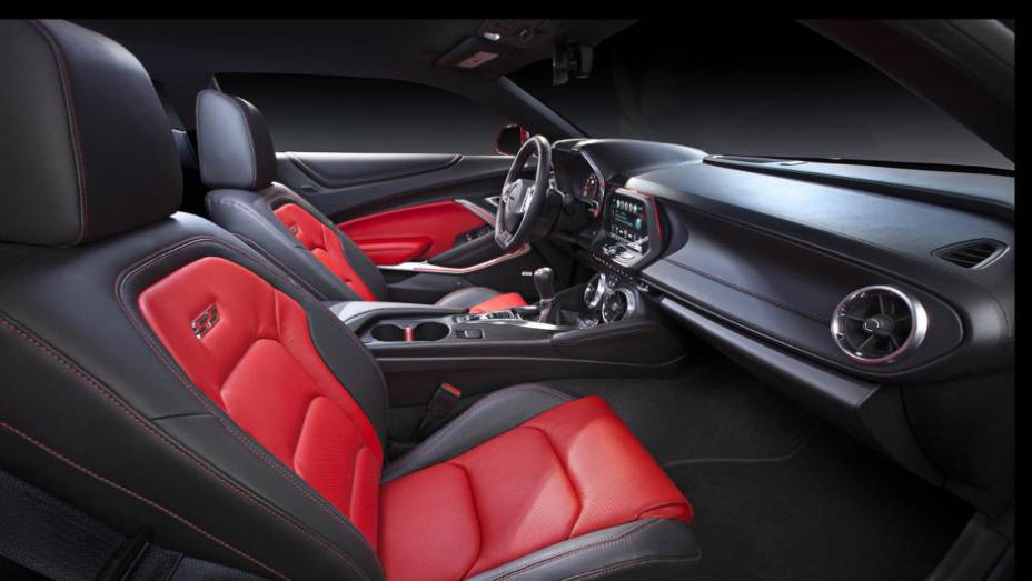 Interior apresenta bancos esportivos em couro com costura contrastante, que também se estende para os painéis de portas e console | <a href="https://preprod.quatrorodas.abril.com.br/noticias/fabricantes/chevrolet-mostra-camaro-2016-865740.shtml" rel="migration">Leia mais</a>