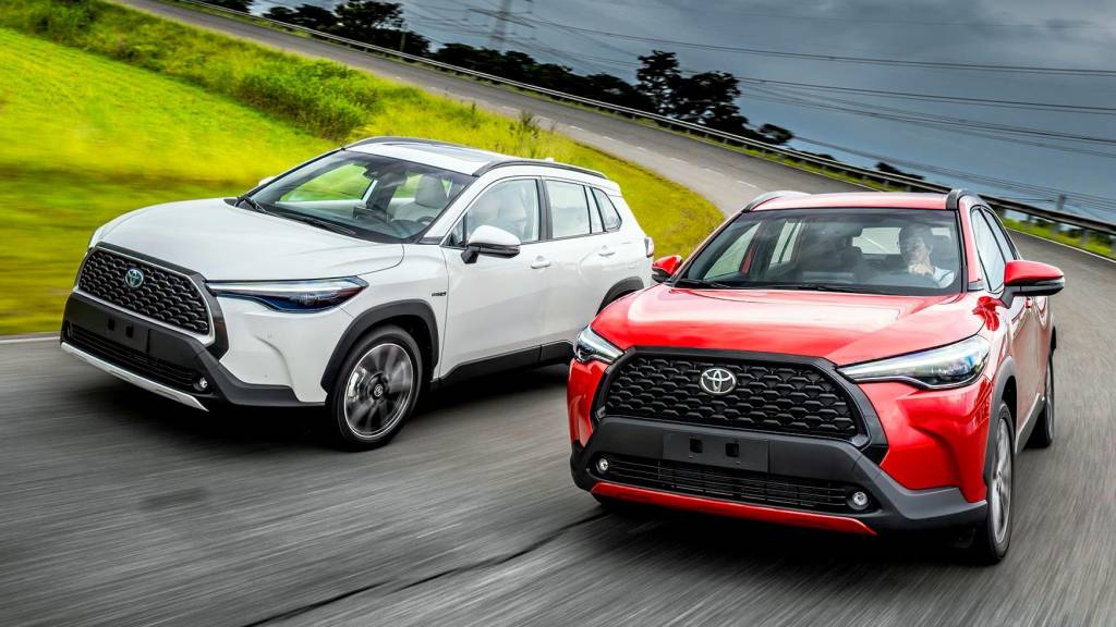 Dois Toyota Corolla Cross 2.0 XRE, um branco e outro vermelho, vistos de 3/4 de frente