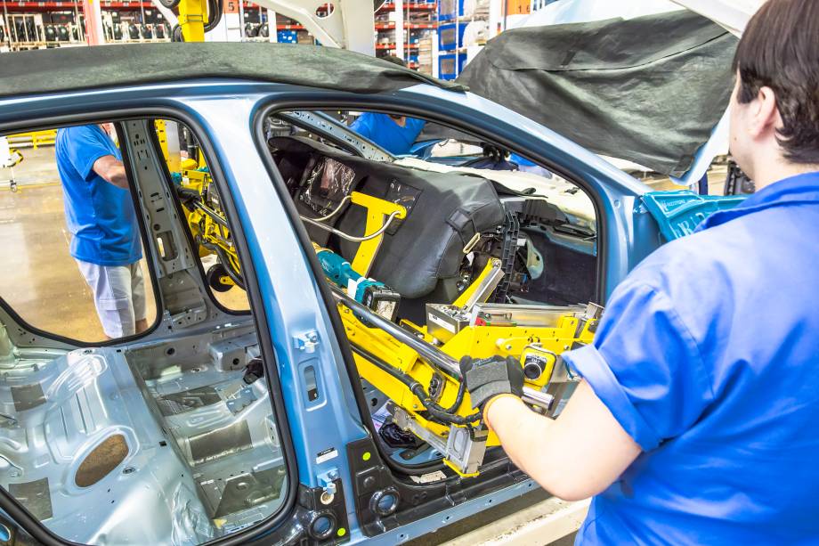 Os trabalhadores posicionam o conjunto do painel e o fixam ao carro