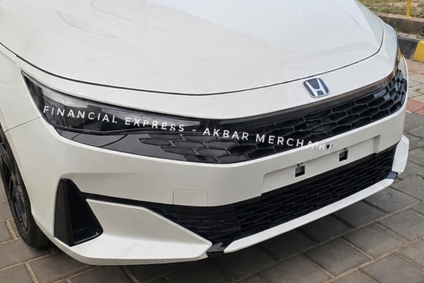 Parte frontal do Honda City 2027, com grade preta em colmeia, far&oacute;is escuros e o emblema Honda. O para-choque tem detalhes pretos.