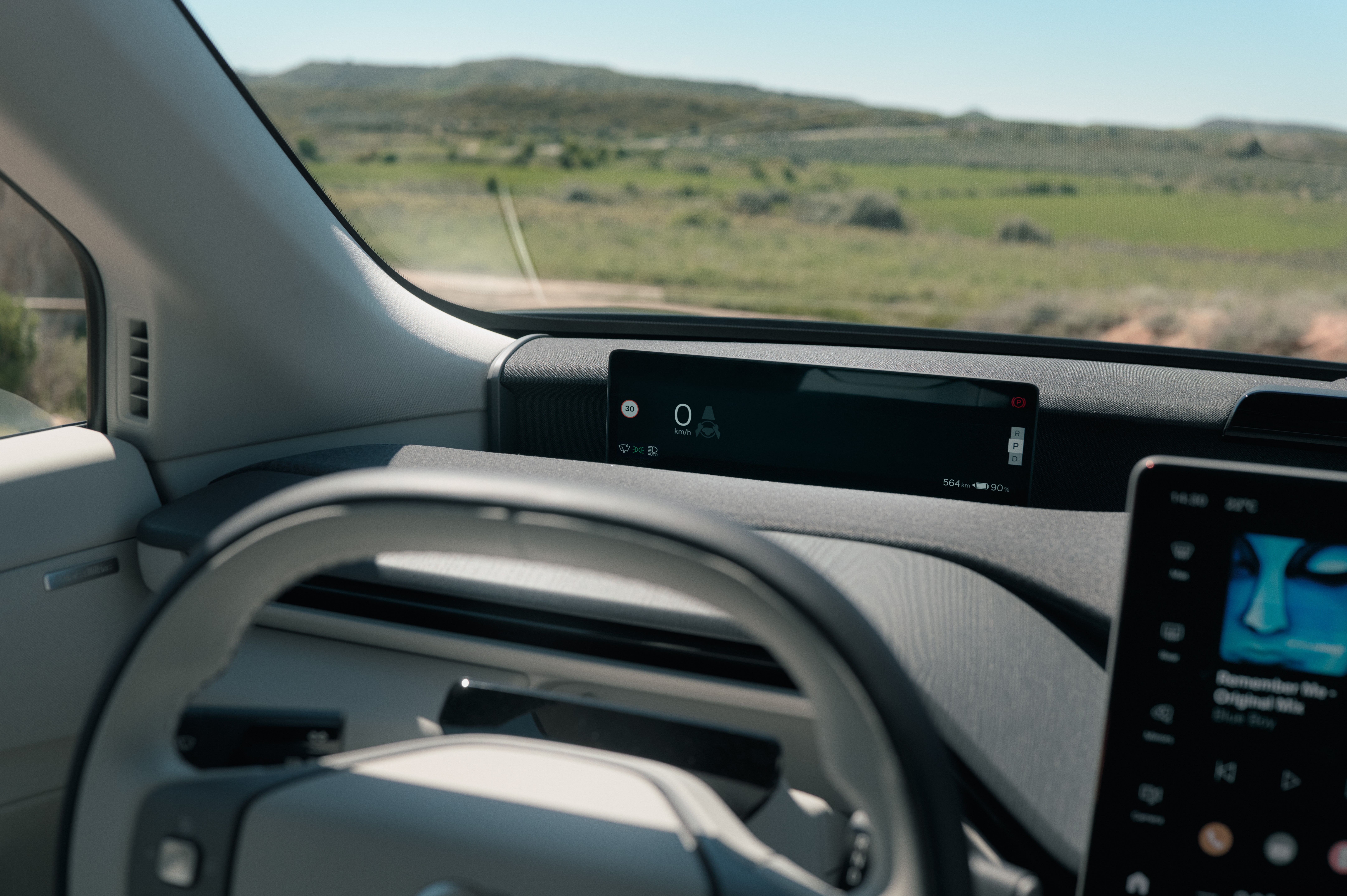 Interior de um carro moderno com volante cinza claro, painel digital exibindo 