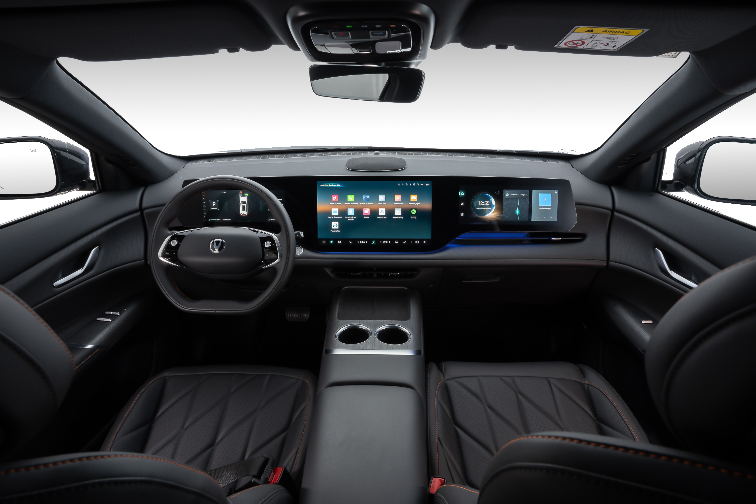Interior de carro moderno com painel digital amplo, volante multifuncional e bancos de couro pretos com costura laranja. O painel exibe &iacute;cones de aplicativos e informa&ccedil;&otilde;es do ve&iacute;culo.