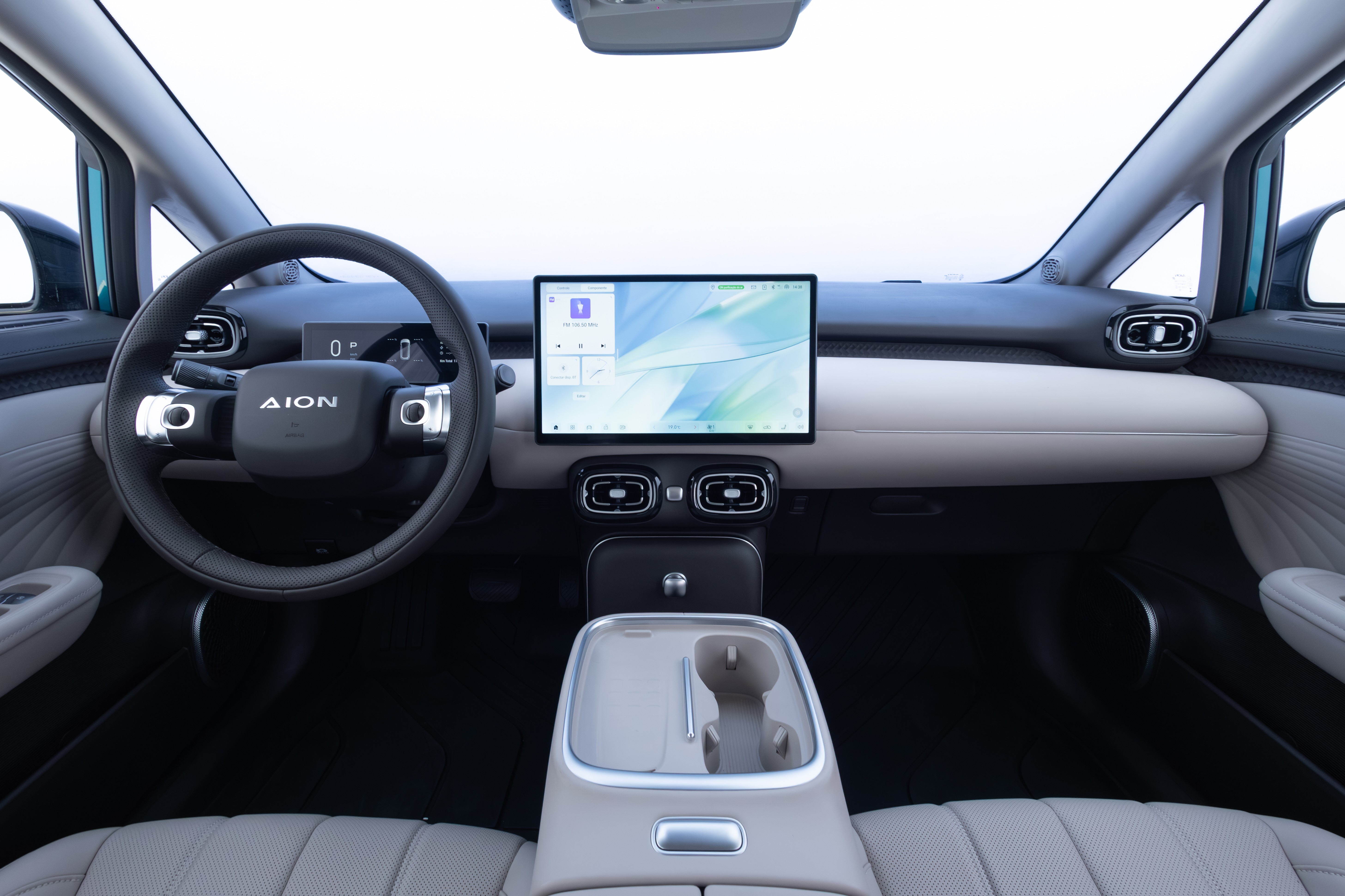 Interior de um carro moderno, com volante preto exibindo o logo 
