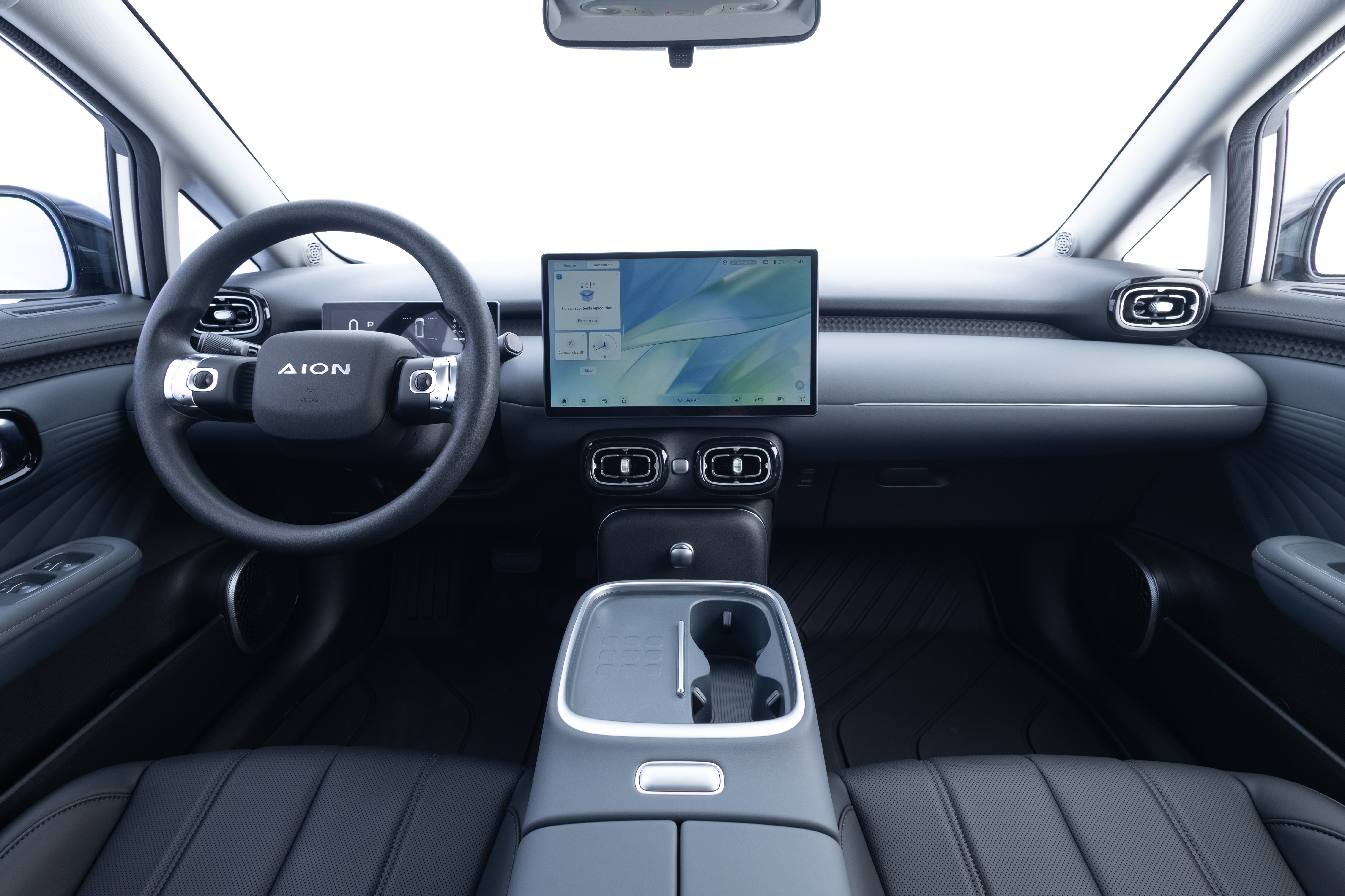 Interior de um carro moderno com volante preto exibindo o logo 
