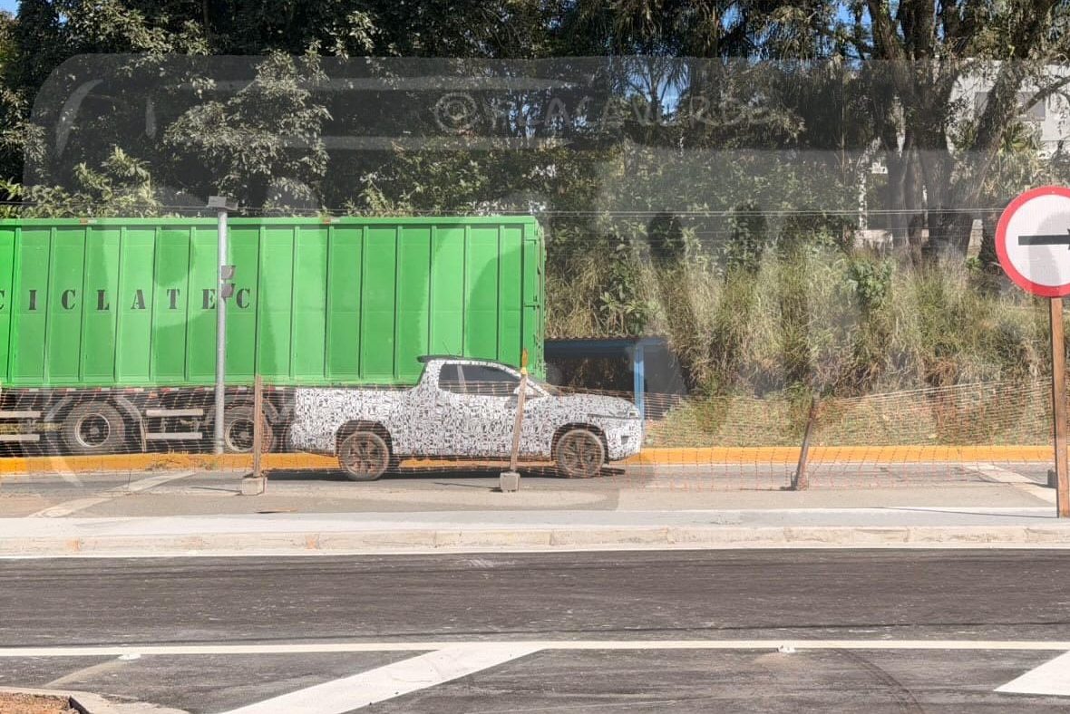 Caminh&atilde;o verde com a palavra CICLATEC e uma picape camuflada estacionados em uma rua, com uma placa de sentido &uacute;nico apontando para a direita