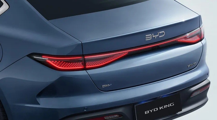 Traseira de um carro azul-marinho, com lanternas vermelhas acesas em uma barra horizontal que atravessa a tampa do porta-malas. O logotipo BYD est&aacute; acima da barra de luz, e BYD KING aparece na placa preta abaixo do para-choque