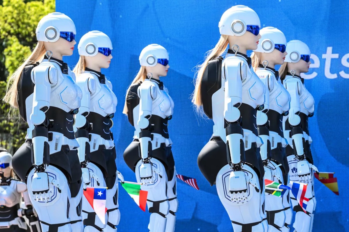 Rob&ocirc;s humanoides femininos, com cabelos loiros e &oacute;culos azuis, enfileirados em um evento, com bandeiras de pa&iacute;ses como Chile e It&aacute;lia presas aos seus bra&ccedil;os, em frente a um fundo azul